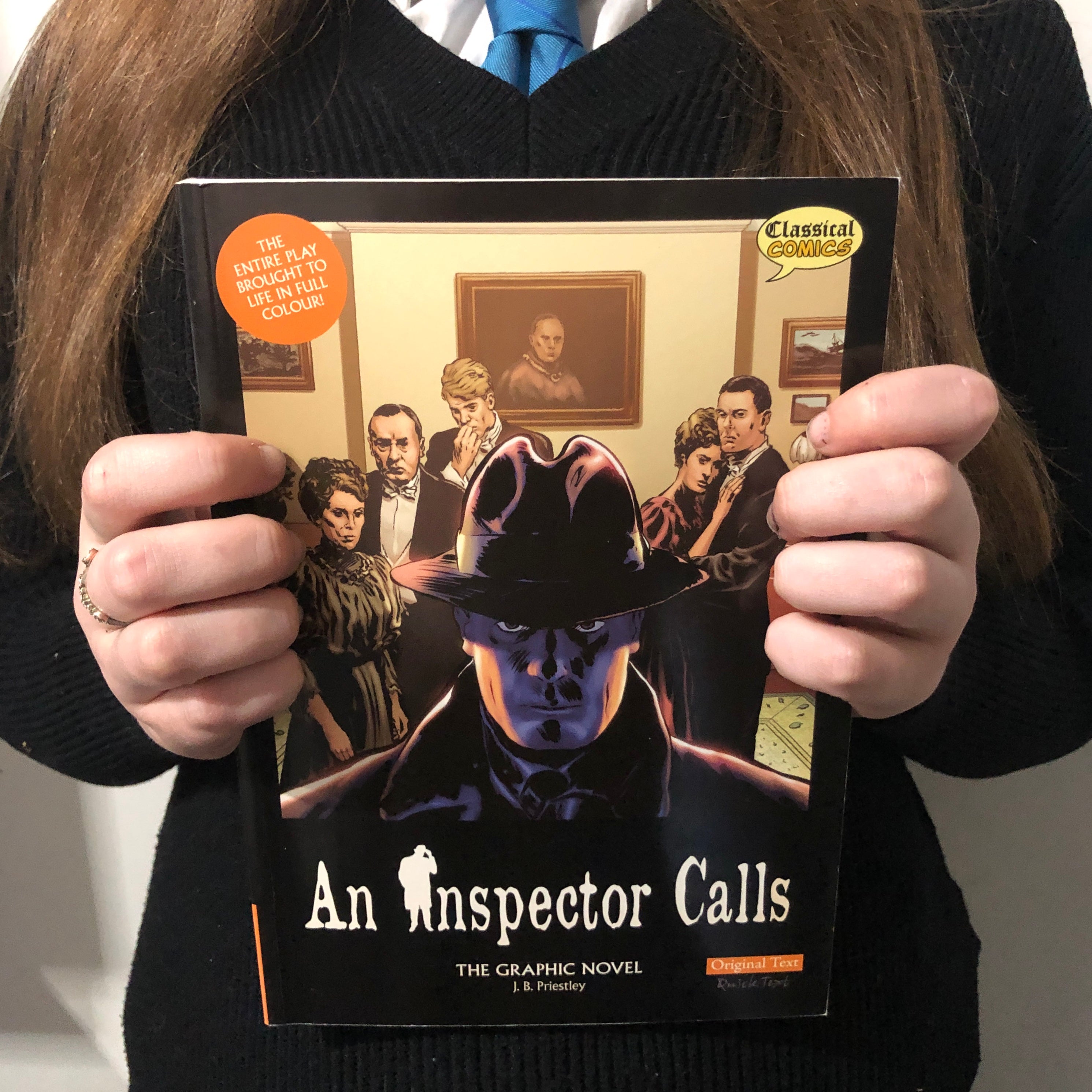 A student holding a copy of An Inspector Calls the graphic novel.